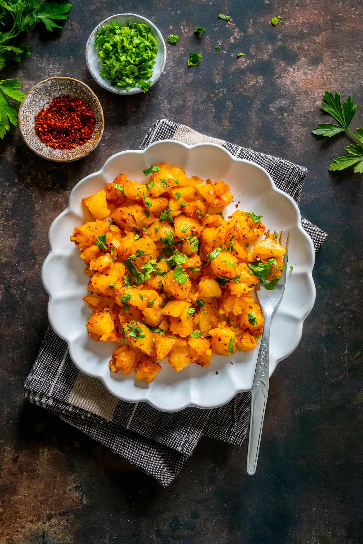 A plate of Patates Kavurma, Turkish potatoes cooked with onion, tomato paste, and spices, garnished with parsley.