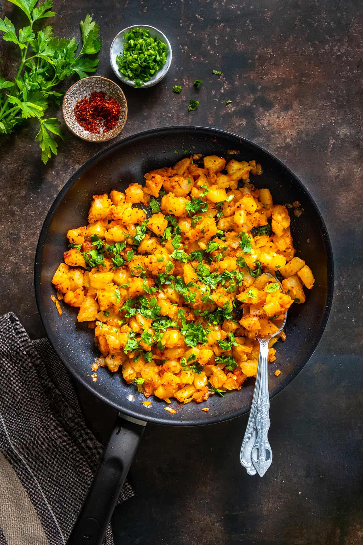 Patates Kavurma cooking in a pan with onion, tomato paste, spices, and parsley.