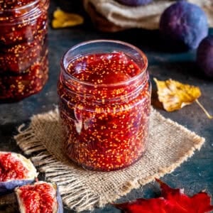 Homemade fig jam in a glass jar with fresh figs around.
