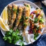 Pinterest graphic showing a plate of crispy fried sardines with lemon, parsley, and salad, labeled “Fried Sardines.”