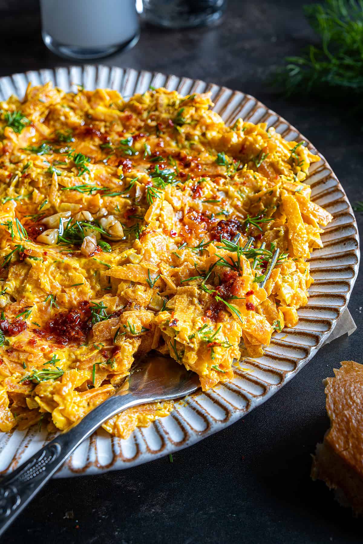 Close-up of Havuç Tarator on a plate, showing its creamy carrot texture, fresh dill, and chili oil topping with a spoon serving a portion.