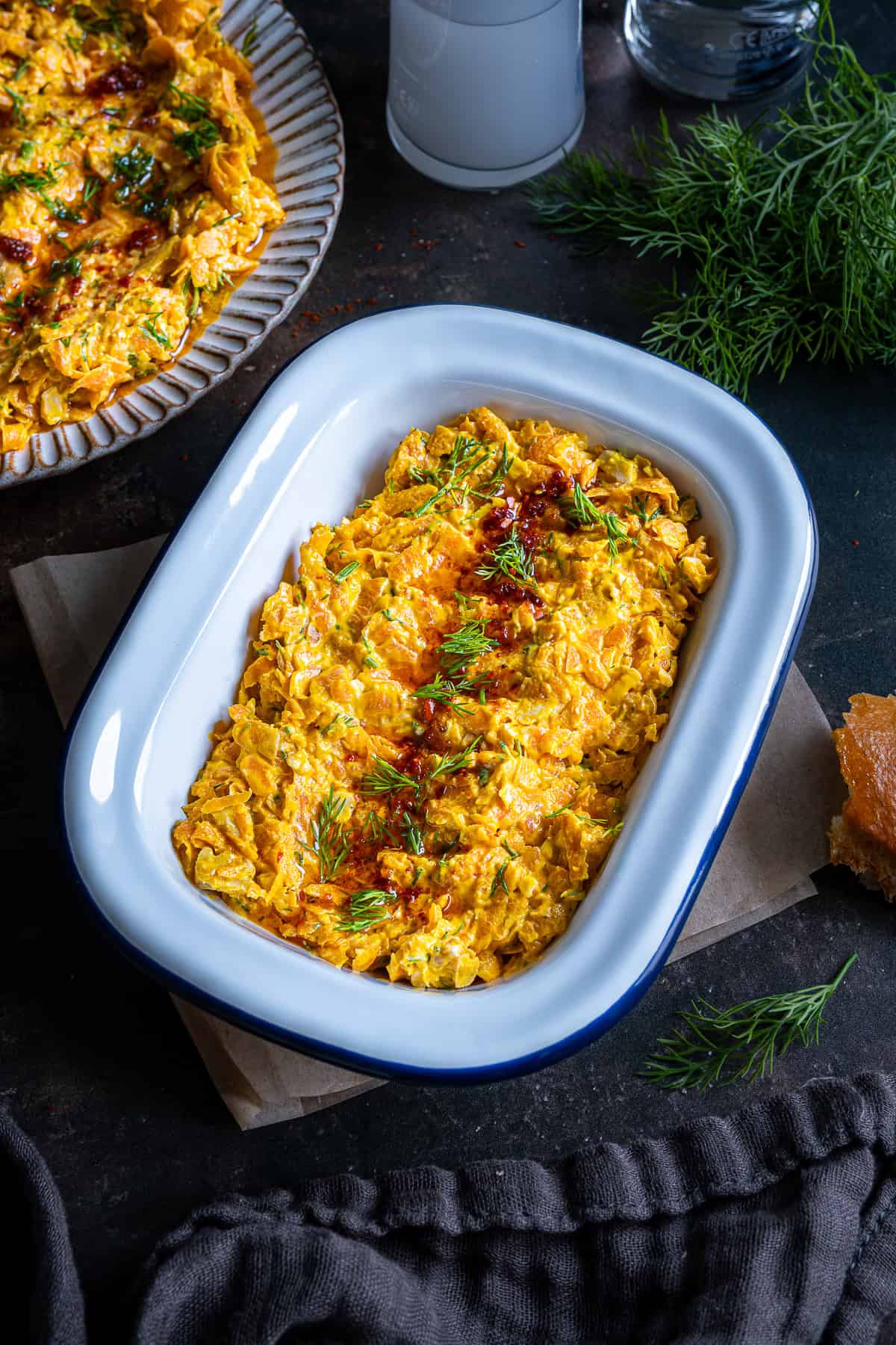 Rectangular dish of Havuç Tarator topped with dill and chili oil, with bread, dill sprigs, and rakı glasses in the background.