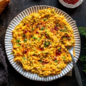 Close-up overhead view of Havuç Tarator on a plate, topped with dill and drizzled with spicy chili oil.
