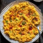 Close-up overhead view of Havuç Tarator on a plate, topped with dill and drizzled with spicy chili oil.