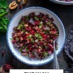 Turkish beet salad served in a white bowl with fresh dill, walnuts, and pomegranate seeds, with extra salad in the background.