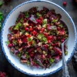 Overhead view of Turkish beetroot salad with dill, walnuts, and pomegranate seeds in a bowl.