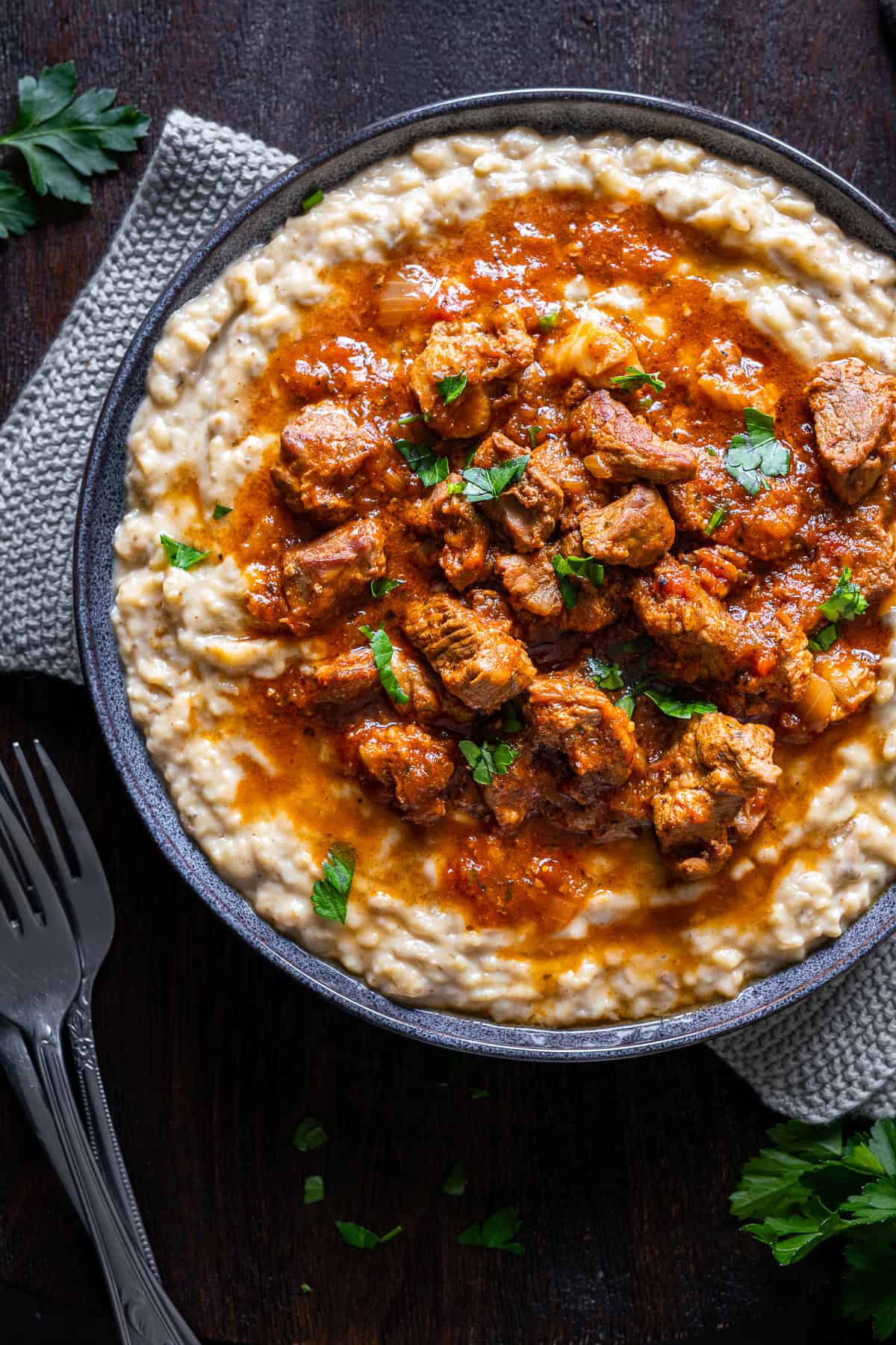 Close-up of Hunkar Begendi with tender lamb stew served over creamy eggplant puree, finished with a parsley garnish.