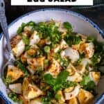 Turkish egg salad with boiled eggs, fresh herbs, and spices in a white bowl with a spoon.