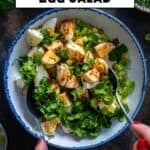 Overhead view of Turkish egg salad being mixed with fresh herbs and green onions, with lemon and olive oil on the side.