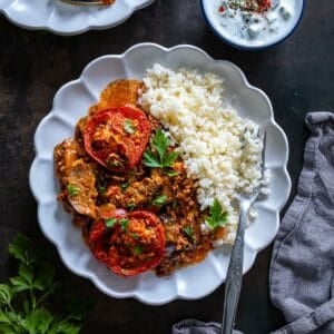 Overhead view of Turkish moussaka with roasted eggplant and ground beef served with rice pilaf and cacık on the side.