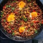 Pinterest pin image of ground beef and eggs breakfast cooked in a skillet with onions, peppers, and runny eggs, with recipe title text overlay.
