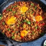 Pinterest pin image showing a skillet of ground beef and eggs breakfast with onions, red peppers, and runny eggs, with recipe title text overlay.