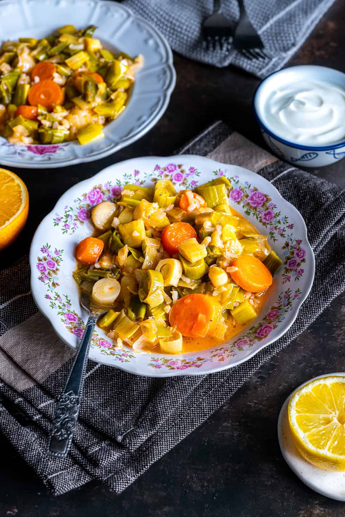 Turkish Leeks in Olive Oil served warm with carrots and rice, alongside yogurt and lemon wedges.