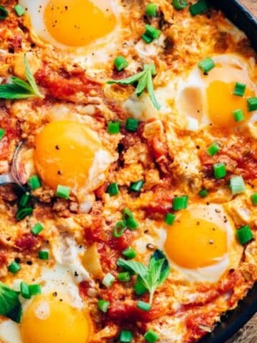 Menemen, (eggs with tomatoes and peppers) in a pan, topped with herbs and soft yolks.
