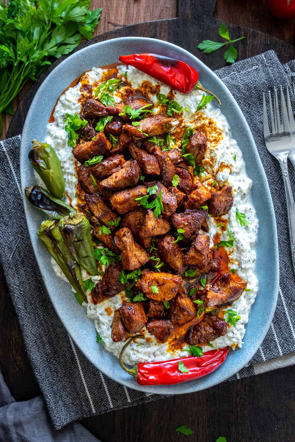 Ali Nazik Kebab garnished with parsley and roasted peppers served on an oval plate.