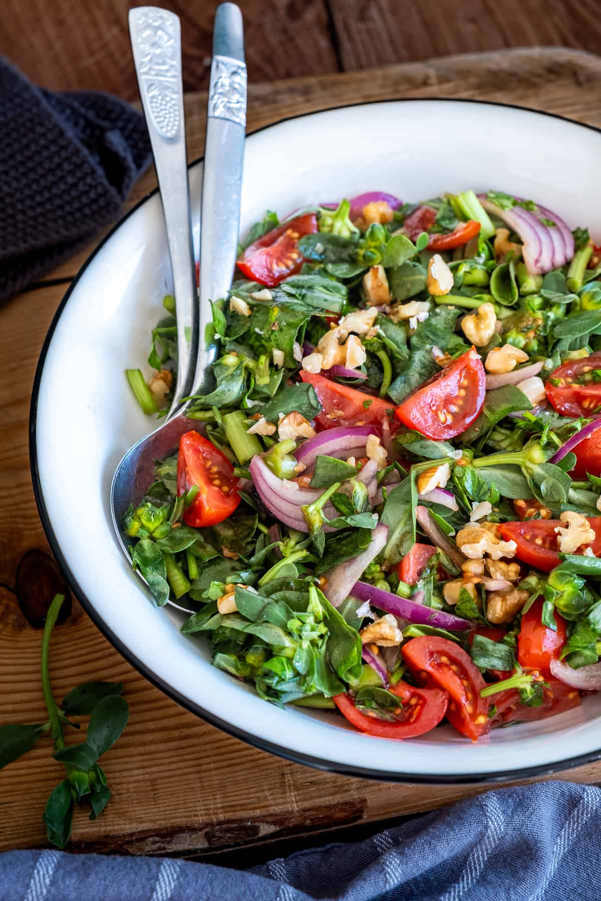 Turkish purslane salad with tomatoes, onions and walnuts served in a white bowl.