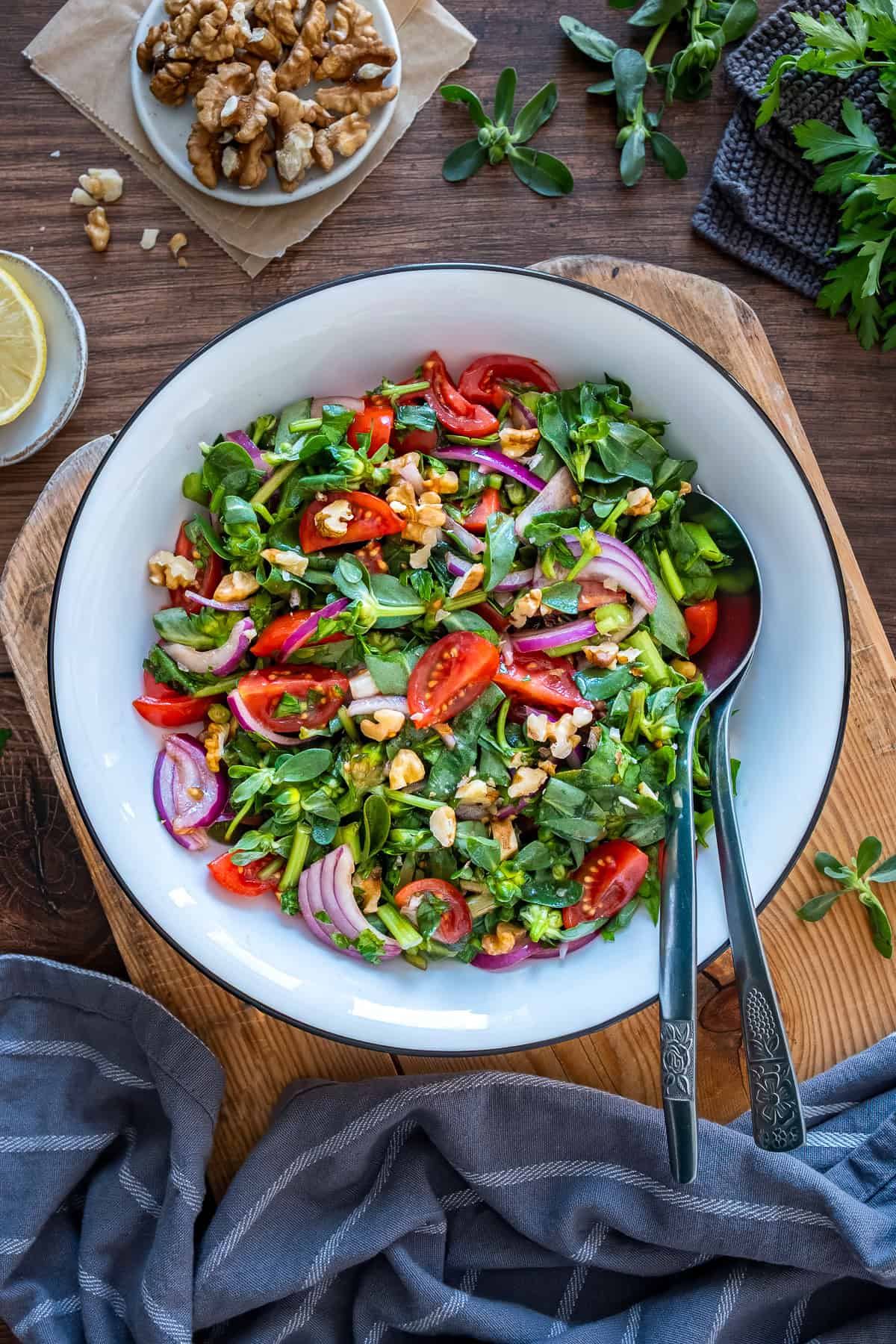 Turkish purslane salad with tomatoes, onions and walnuts served in a large white bowl.