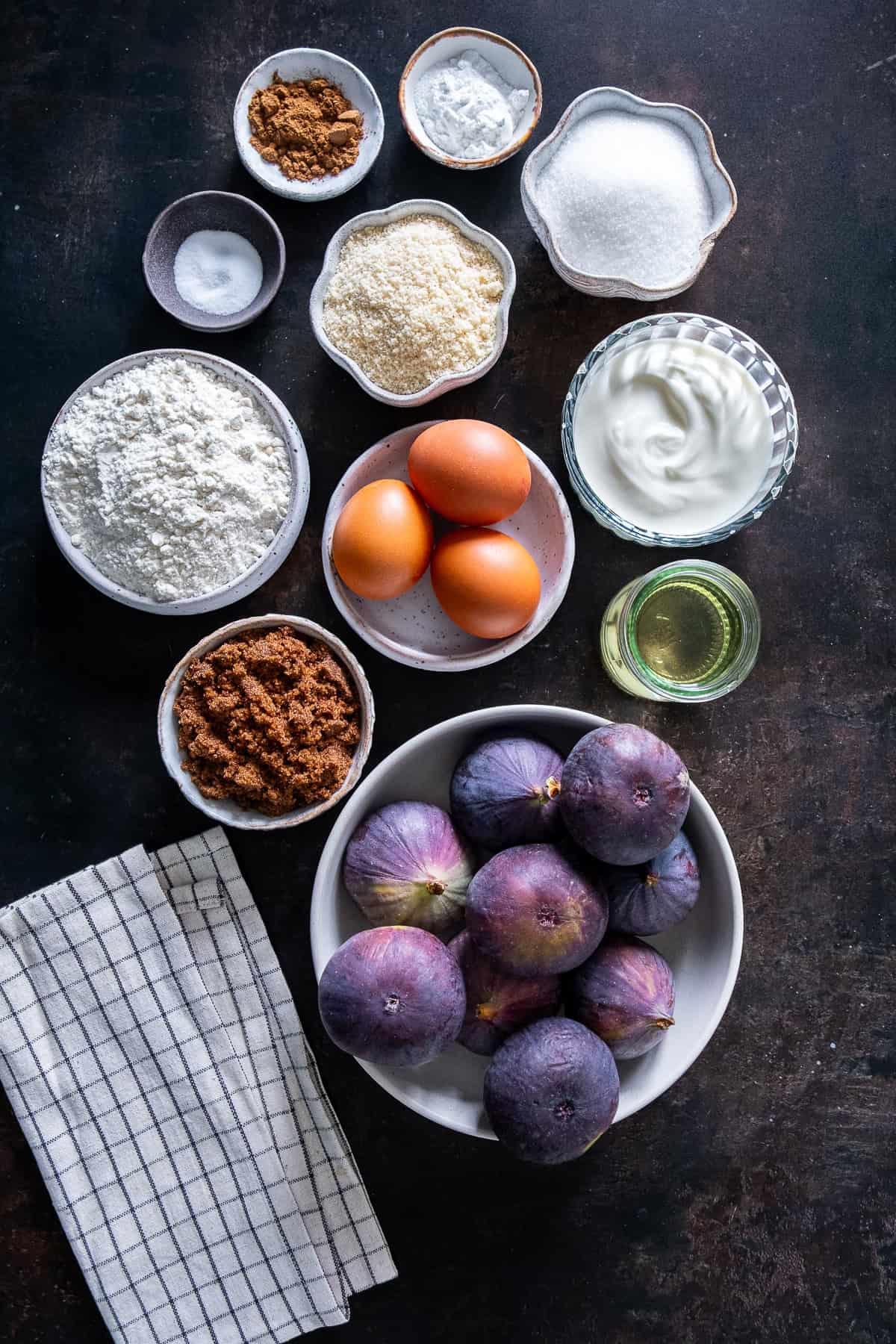 Fresh fig cake ingredients including fresh figs, almond flour, yogurt, olive oil, eggs, flour, sugar and cinnamon.