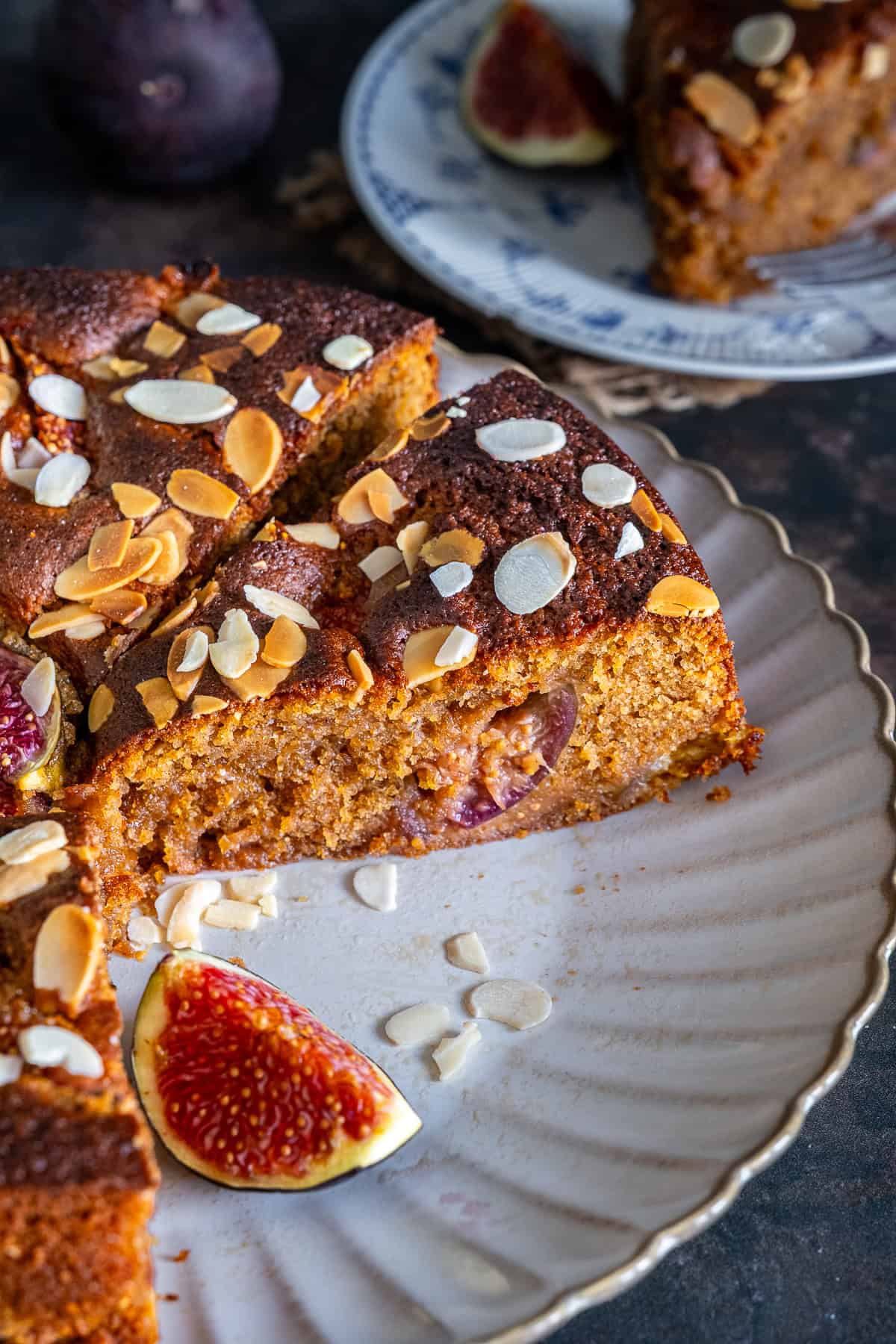 Close-up of fresh fig cake showing its soft, moist crumb with pieces of fig inside and flaked almonds on top.