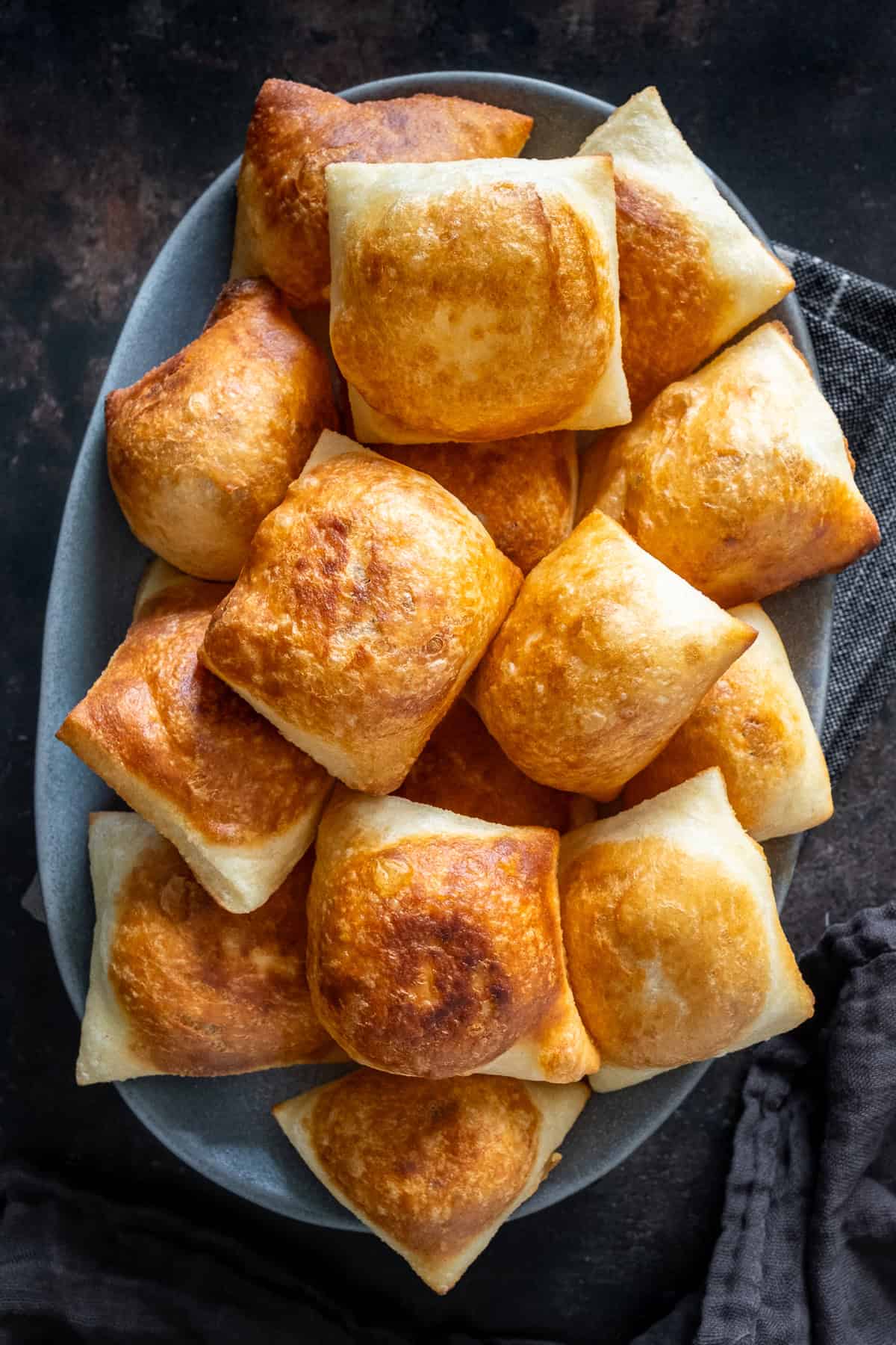 Overhead view of a platter piled with golden, puffed Turkish pişi fried dough.