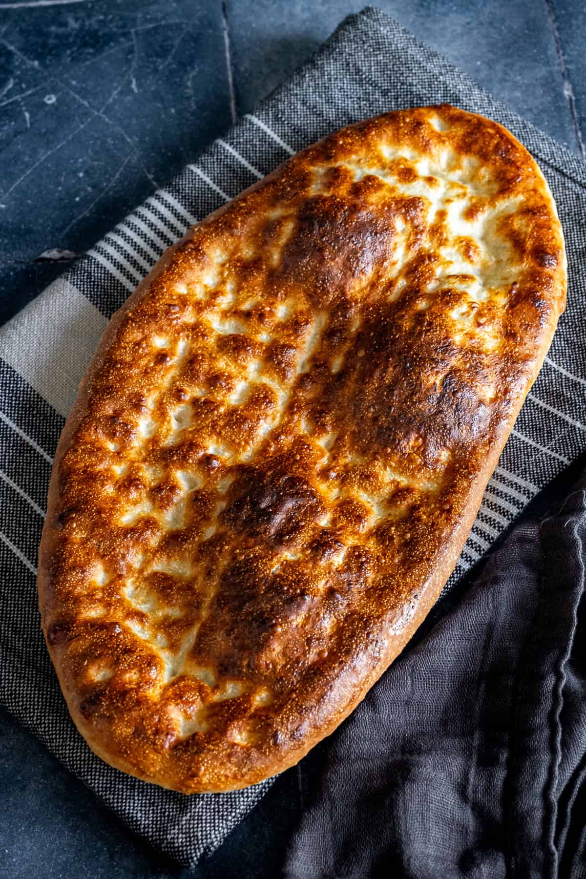 Close-up of freshly baked tirnak pide with a golden-brown crust and traditional fingertip pattern.